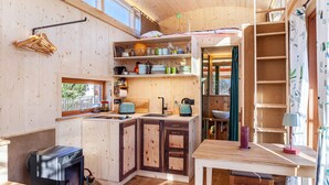 A compact kitchen with wooden cabinets, a stove, and a window. - Charming Tiny House “Loft Süd” with Mountain View, Wi-Fi, Terrace and Garden (Unterammergau)