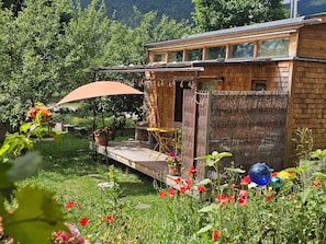 Eine Holzdiele mit einer Terrasse, umgeben von üppiger Vegetation und einem Bergpanorama.