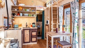 A wooden interior with a kitchen, dining area, and large windows. - Charming Tiny House “Loft Süd” with Mountain View, Wi-Fi, Terrace and Garden (Unterammergau)