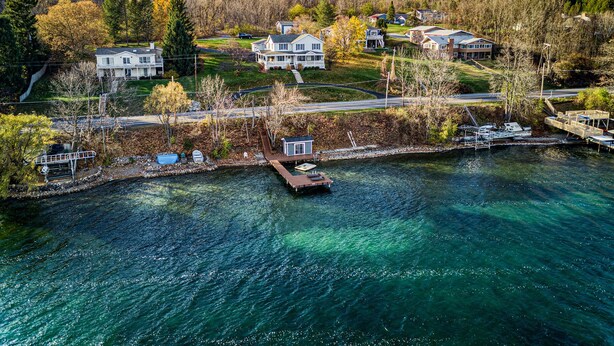 A waterfront property with multiple houses, a dock, and a clear view of the water. - Enjoy swimming/boating in the lake, Fall Foliage, Wine trail, Skiing and Hiking (Canandaigua)