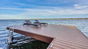 A wooden deck extending into a body of water with two lounge chairs and a ladder. - Enjoy swimming/boating in the lake, Fall Foliage, Wine trail, Skiing and Hiking (Canandaigua)