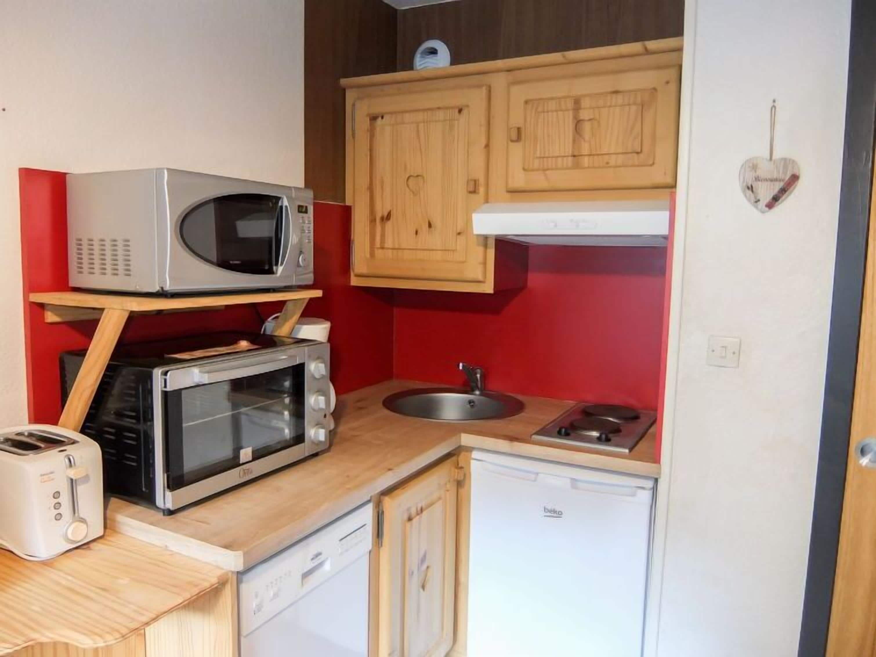 A compact kitchenette with a microwave, toaster, and dishwasher.