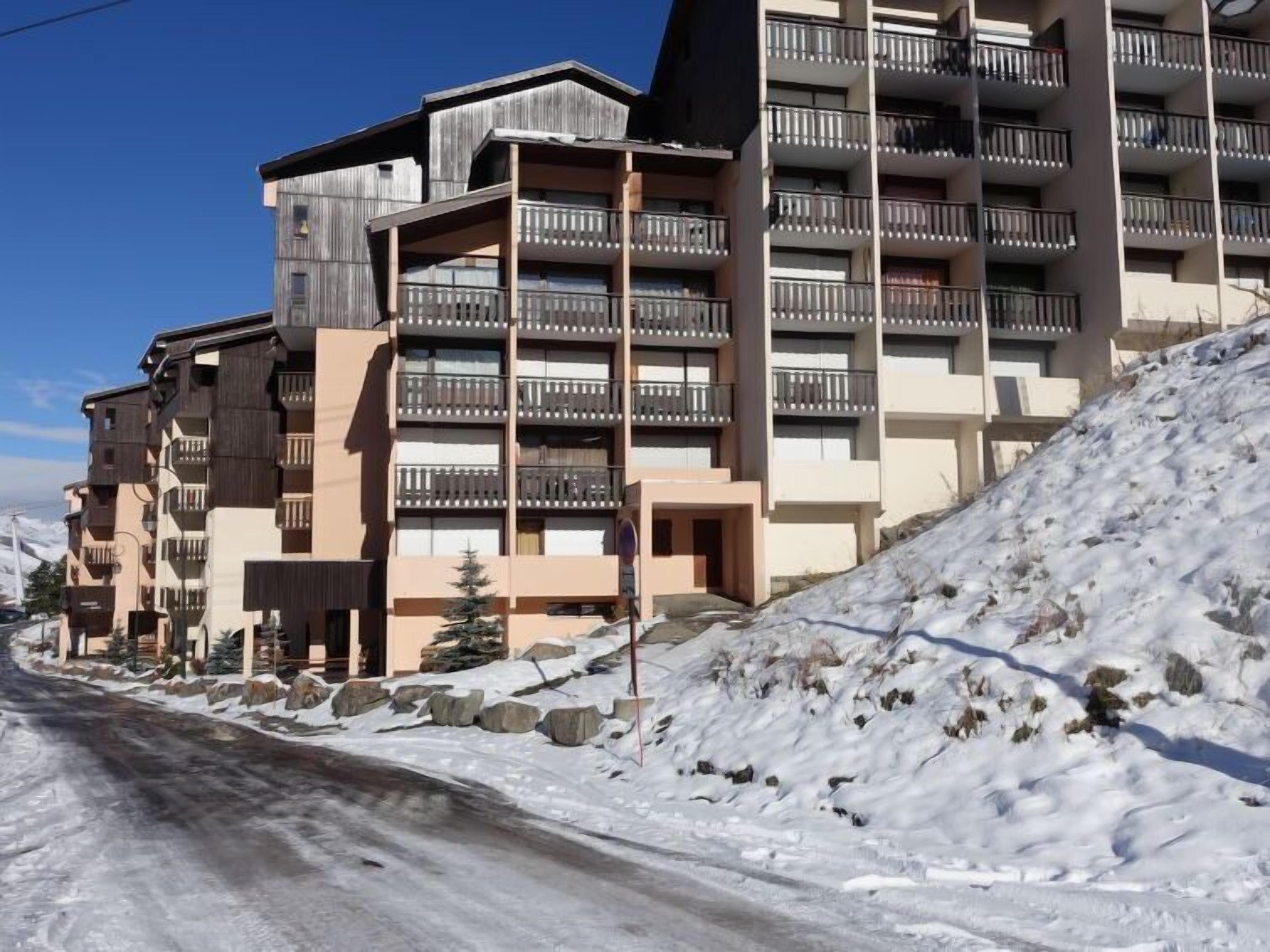 A multi-story hotel with balconies, a snowy landscape, and a clear sky.