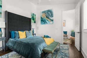 Una camera da letto moderna con un letto grande, una panca e opere d'arte alle pareti.