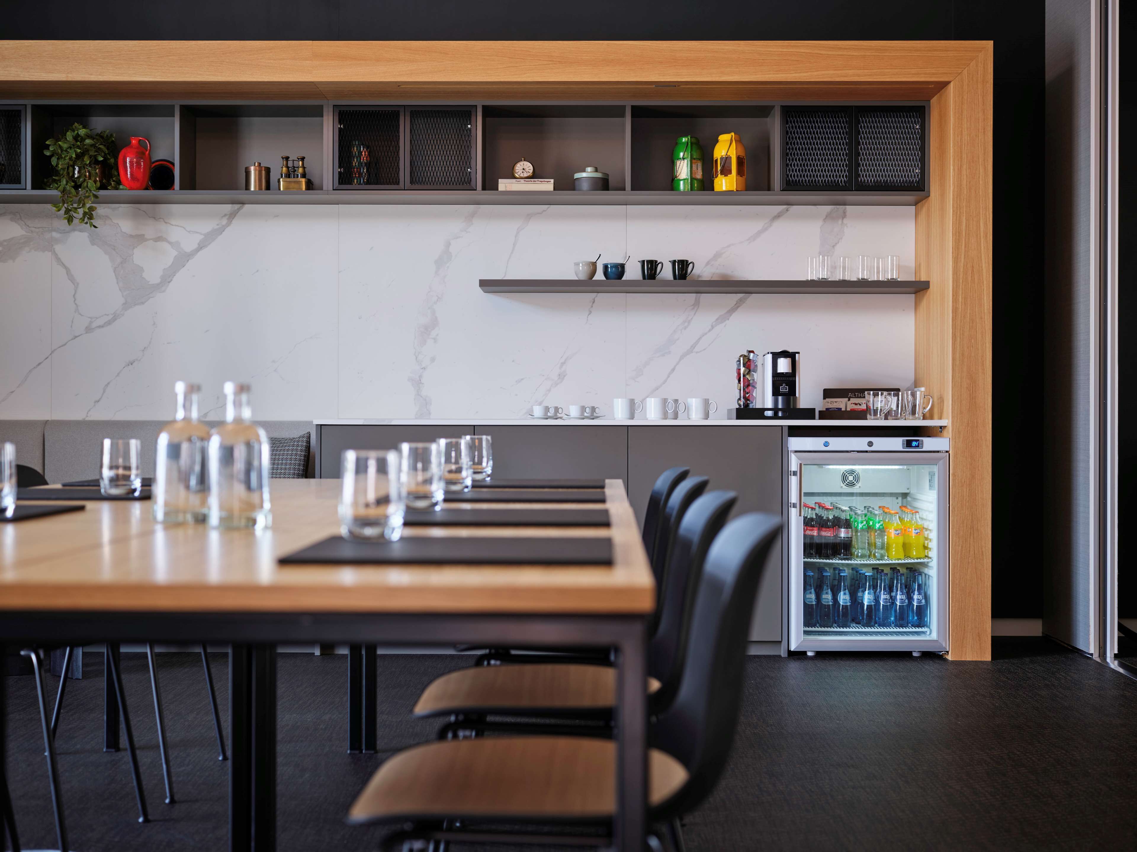 Une cuisine moderne dotée d’un pare-feu en marbre, d’une machine à café intégrée et d’un mini-réfrigérateur rempli de boissons.