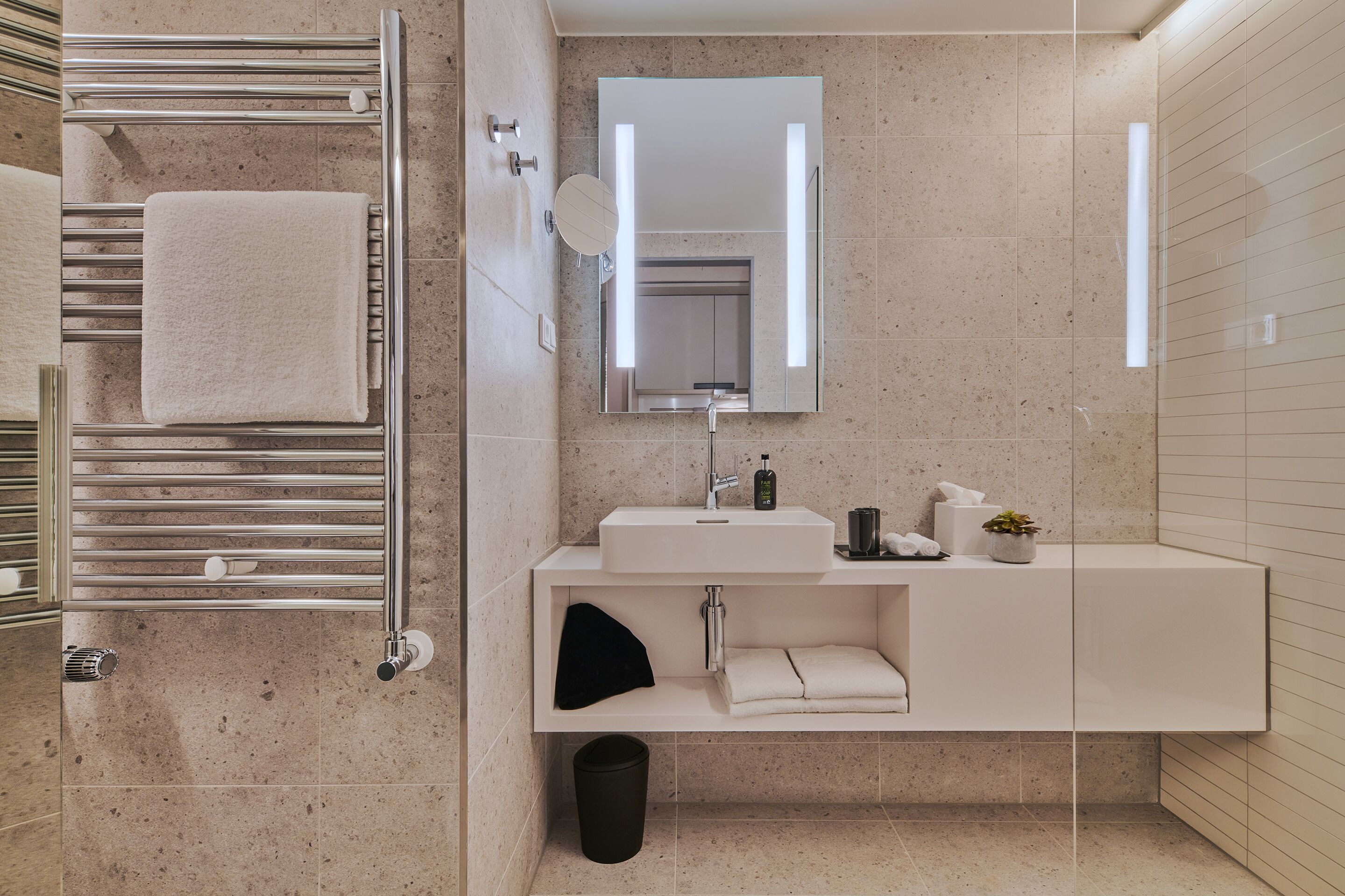 Un baño moderno con un toallero, un lavabo, un espejo y un cesto de basura.
