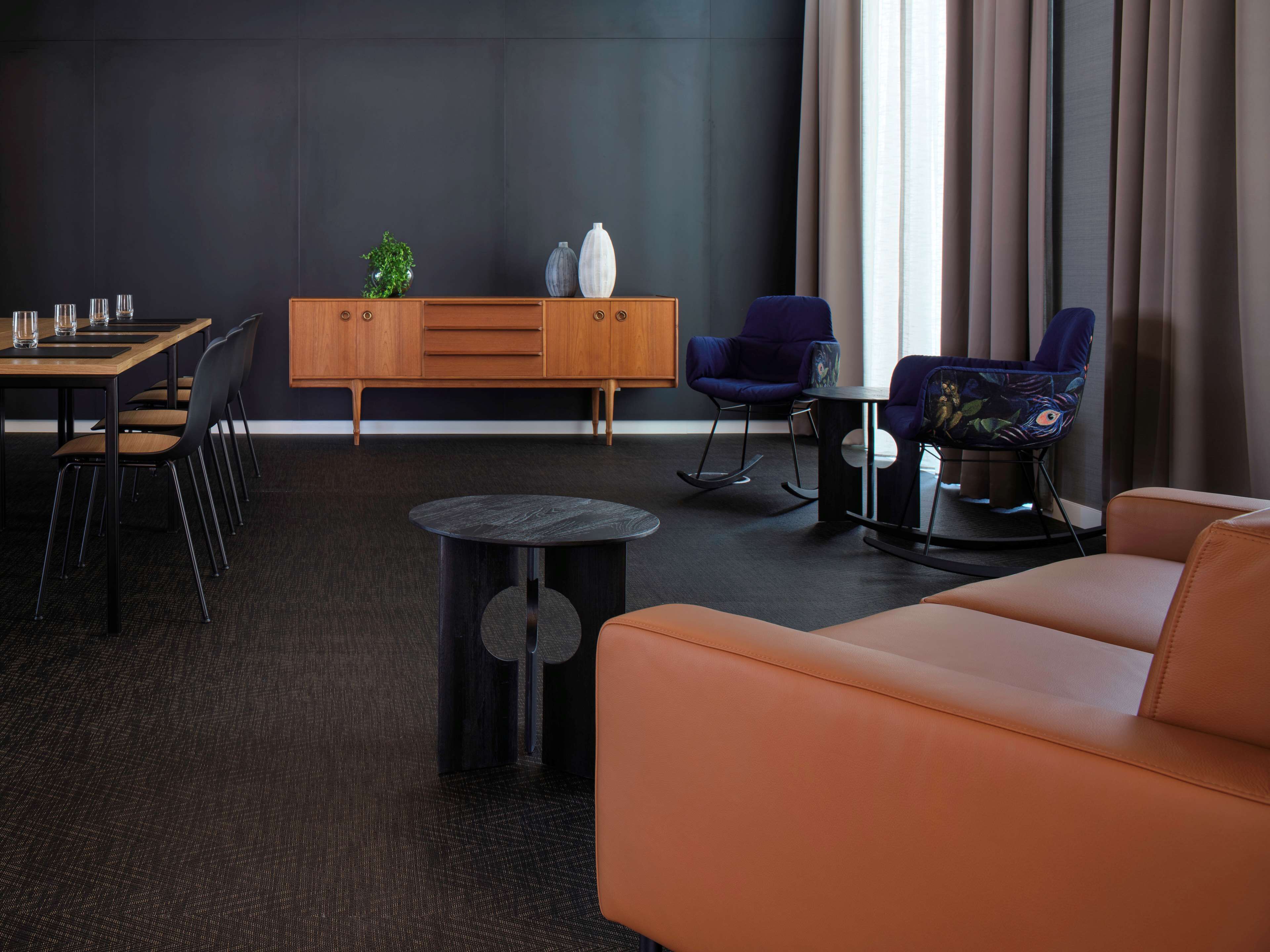 Una habitación de hotel moderna con zona de comedor, un sofá y dos sillones mecedores.
