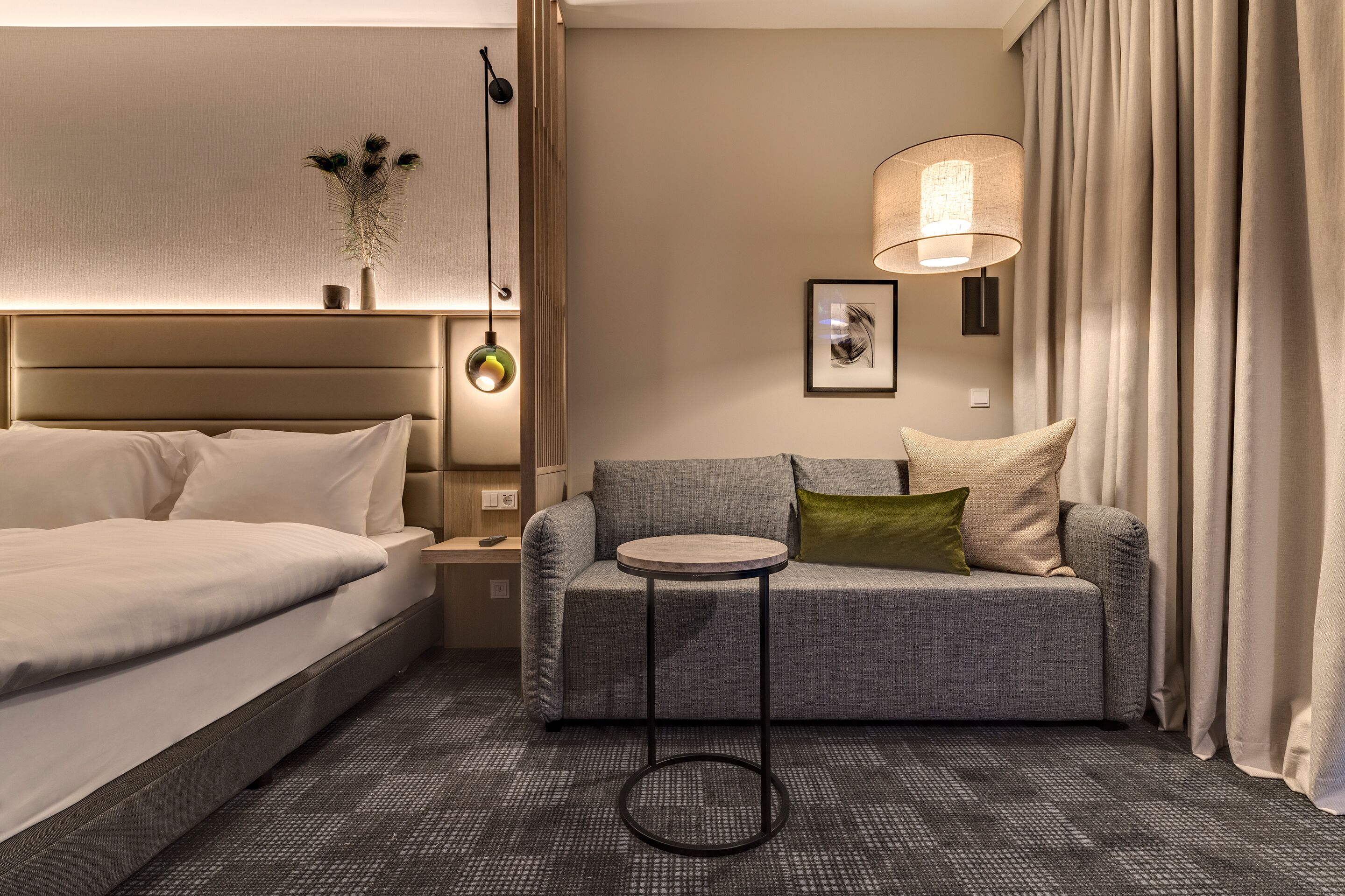 Une chambre d’hôtel avec un lit, un canapé, une petite table ronde et une lampe.