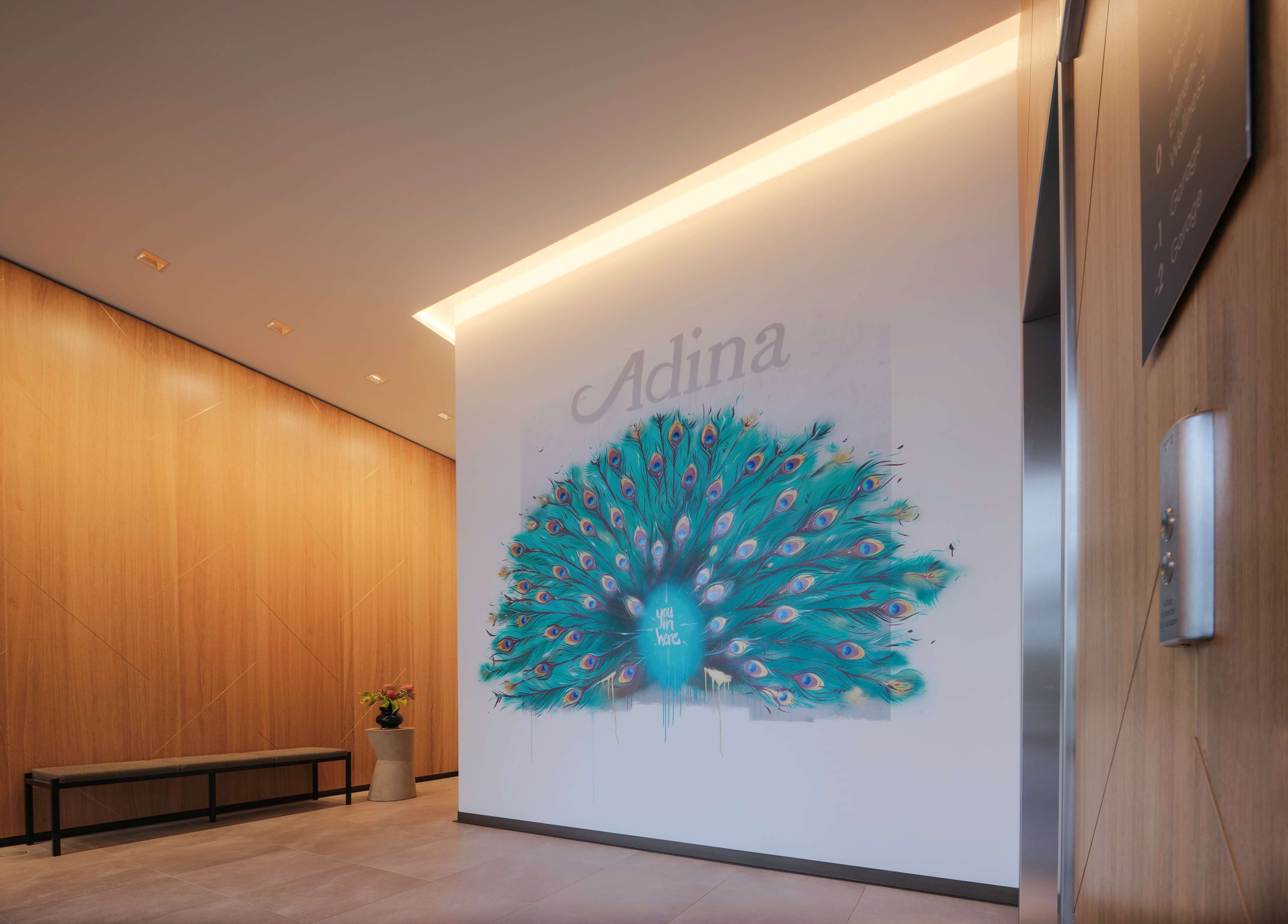 A modern interior with a peacock mural, a bench, and a potted plant.