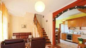 Ein Wohnzimmer mit einem braunen Ledersofa, einem Couchtisch und einer Treppe, die in einen Küchenbereich führt.