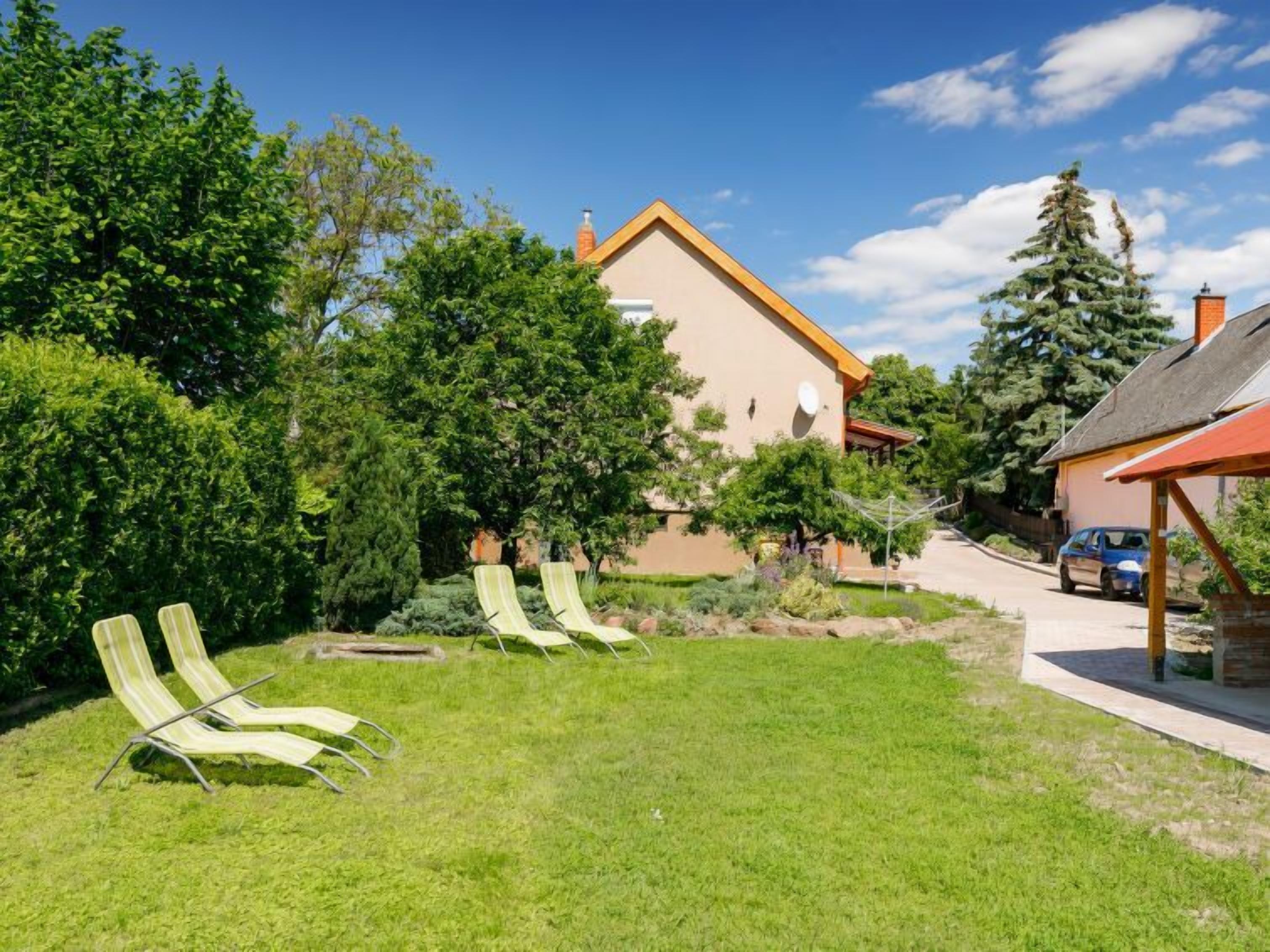 A house with a sloped roof, a covered porch, and a lawn with two lounge chairs.