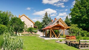 Ein Haus mit großem Garten, einer hölzernen Struktur und blauem Himmel.