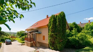 Ein Haus mit rotem Dach, einer überdachten Veranda und einem Garten mit einem Weg.