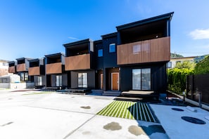 Un moderno edificio residencial con varios balcones y un amplio patio.