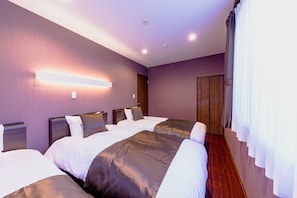 A hotel room with three beds, a wooden wardrobe, and a modern light fixture on the wall. - Mt. Fuji Resort Club-IKI- (Fujikawaguchiko)