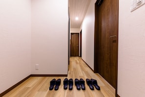 A hallway with wooden flooring and white walls, leading to a door at the end. - Mt. Fuji Resort Club-IKI- (Fujikawaguchiko)