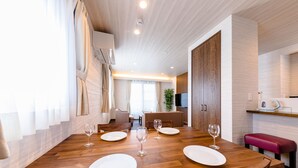A modern dining area with a wooden table set for four, a red bench, and a kitchen area with a microwave and kettle. - Mt. Fuji Resort Club-RIN- (Fujikawaguchiko)