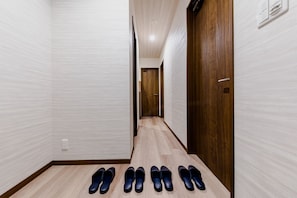 A hallway with a wooden floor and white walls. There are four pairs of shoes lined up on the floor. - Mt. Fuji Resort Club-RIN- (Fujikawaguchiko)