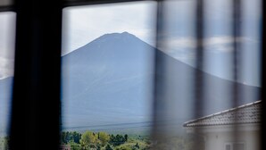A mountain view through a window with a building in the foreground. - Mt. Fuji Resort Club-RIN- (Fujikawaguchiko)
