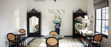 Un comedor con piso estampado, una araña y un letrero en la pared que dice "MOOI GUEST HOUSE".