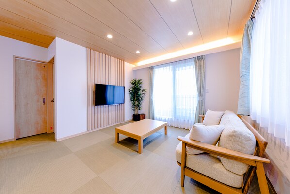 A modern living room with a wooden floor, a sofa, a coffee table, a flat-screen TV, and a potted plant. - Mt. Fuji Resort Club-MIYABI- (Fujikawaguchiko)