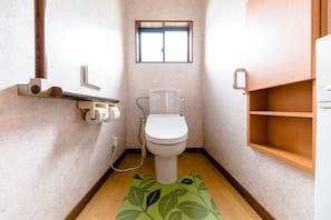 A small bathroom with a toilet, a window, and a wooden shelf. - iine (Fujikawaguchiko)