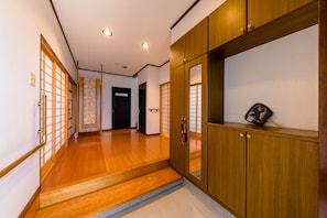 A hallway with wooden flooring, a traditional Japanese sliding door, and a small shelf with a bag. - iine (Fujikawaguchiko)