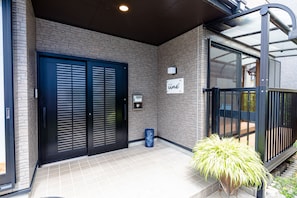 A building entrance with a brick facade, a black door, and a sign that reads "ine". - iine (Fujikawaguchiko)