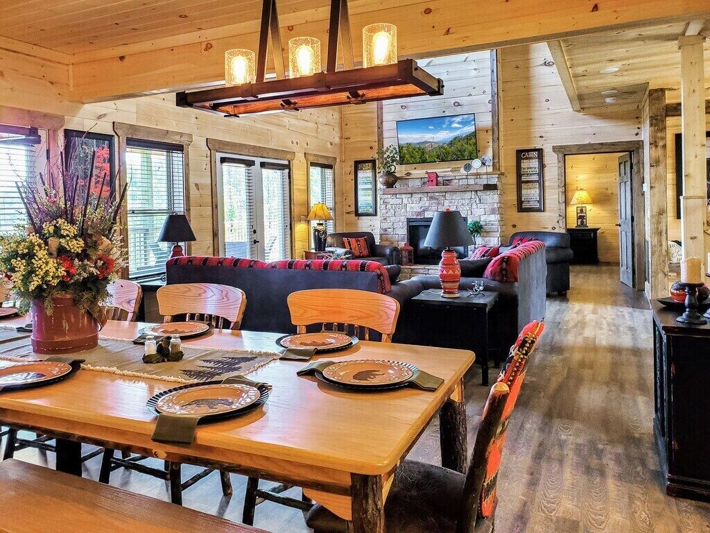 A cozy cabin interior with a dining area, a fireplace, and a living room.