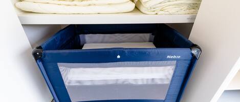 A storage area with neatly stacked bedding and a blue baby stroller with wheels.