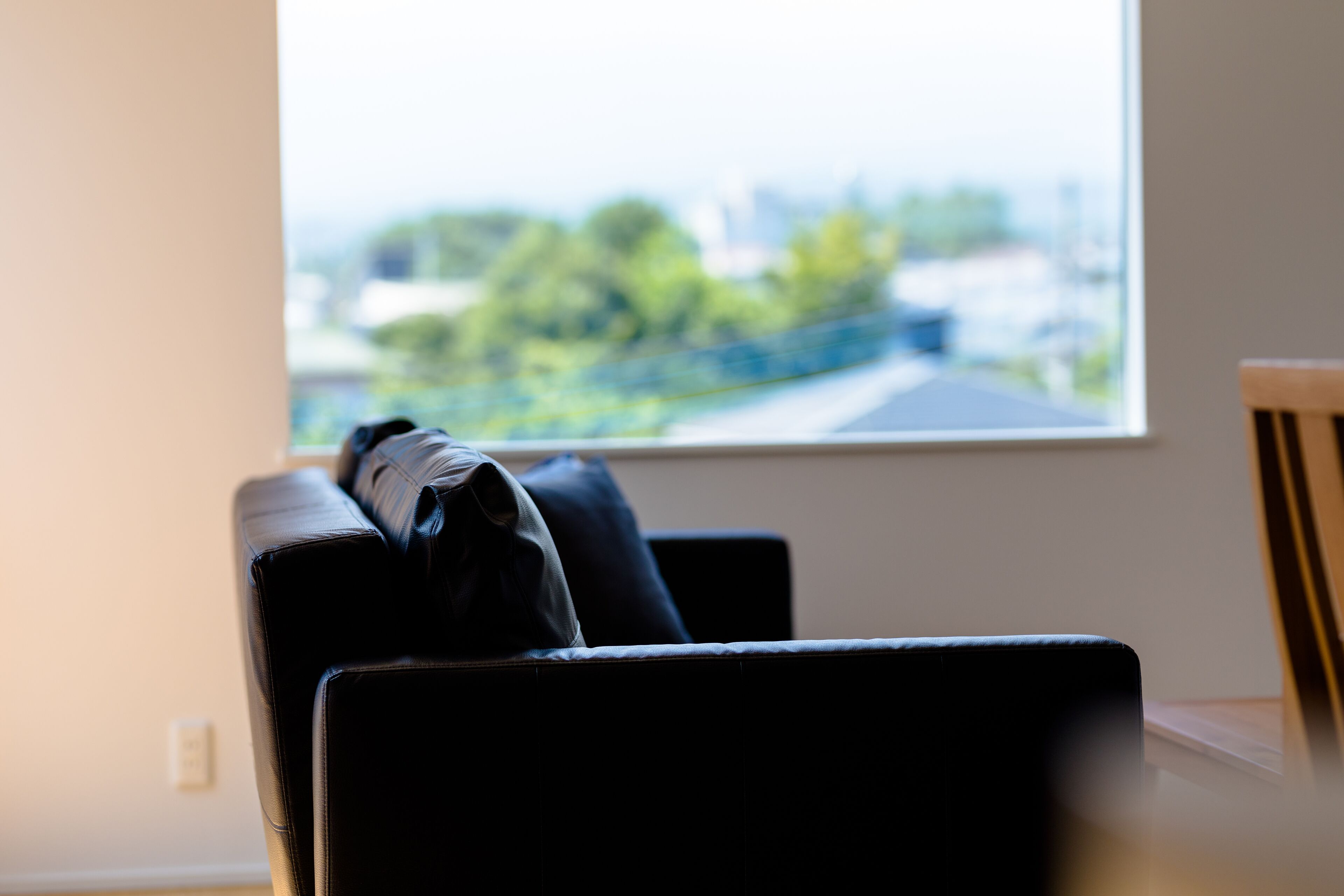 A room with a window, a black leather chair, and a wooden chair.
