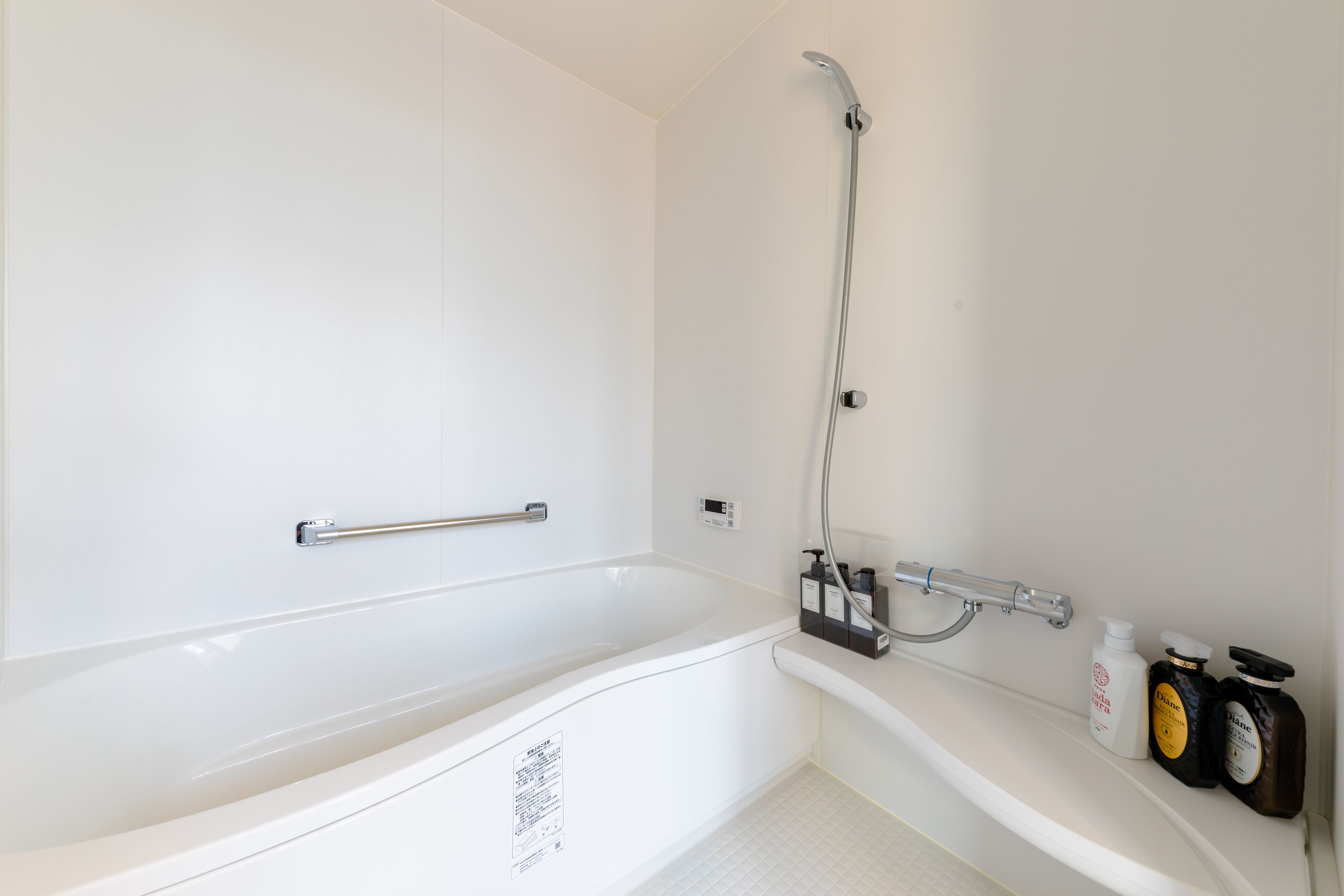 Une salle de bain moderne avec une baignoire blanche, une douche et un meuble-lavabo avec des articles de toilette.