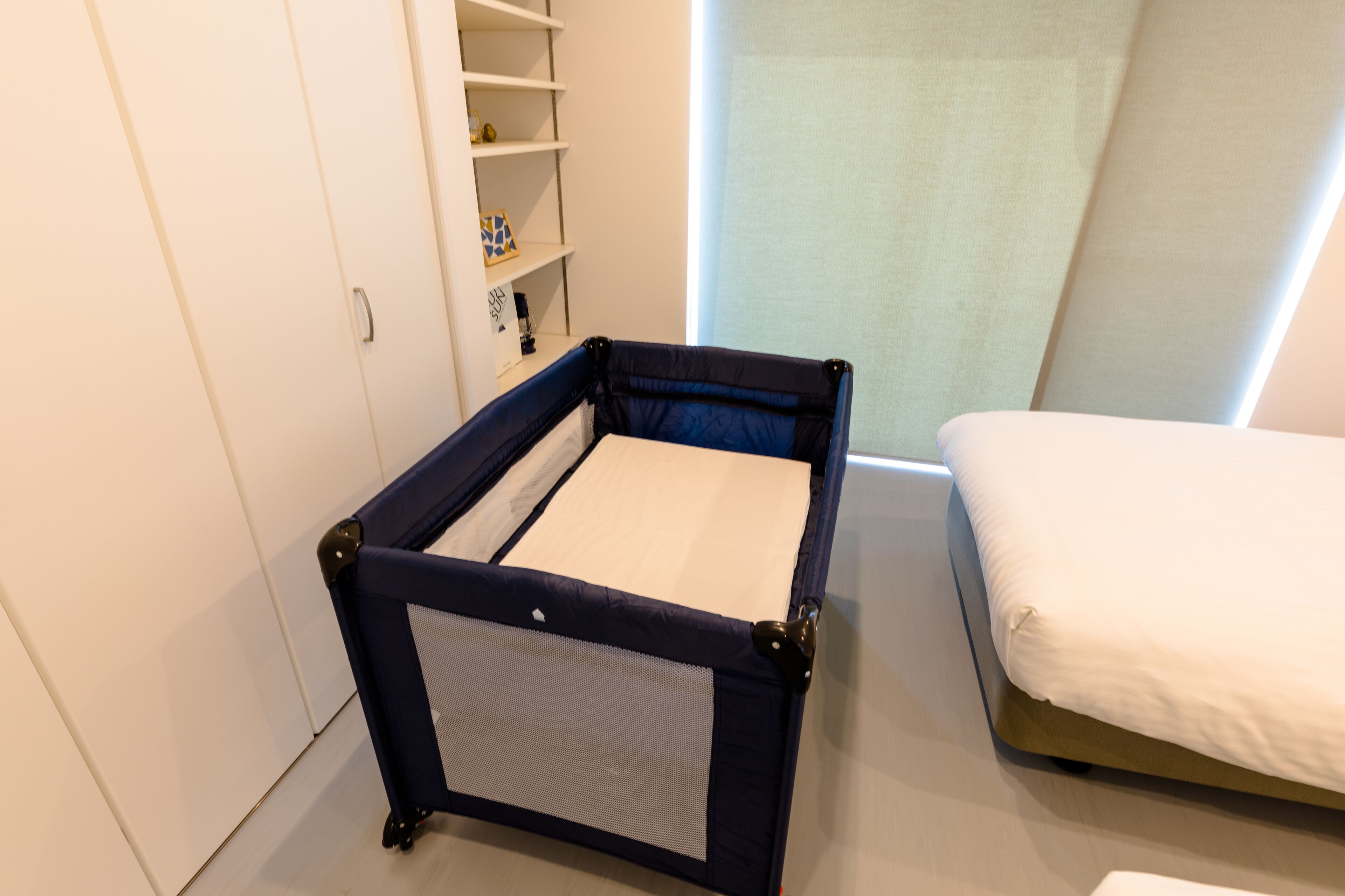 A compact room with a bed, a small desk, and a storage unit.