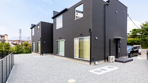 A modern two-story building with a flat roof, large windows, and a car parked in front. - Frame View Mt.Fuji Villa West (Fujikawaguchiko)
