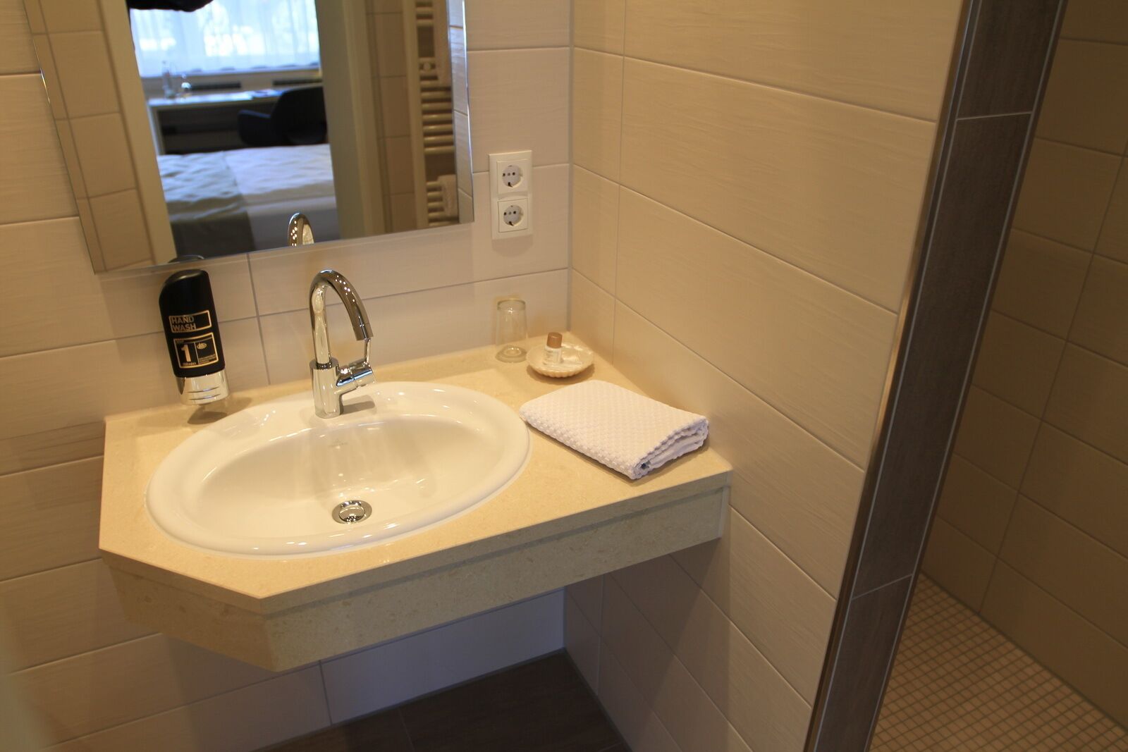 Un baño con lavamanos, espejo y dispensador de jabón.