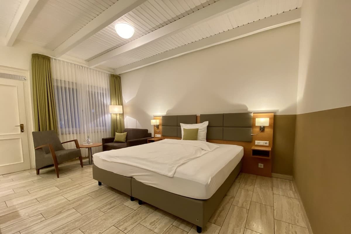 Een hotelkamer met een groot bed, een bureau, een stoel en een raam met gordijnen.