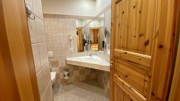 A bathroom with a wooden door, a sink, a toilet, and a mirror.