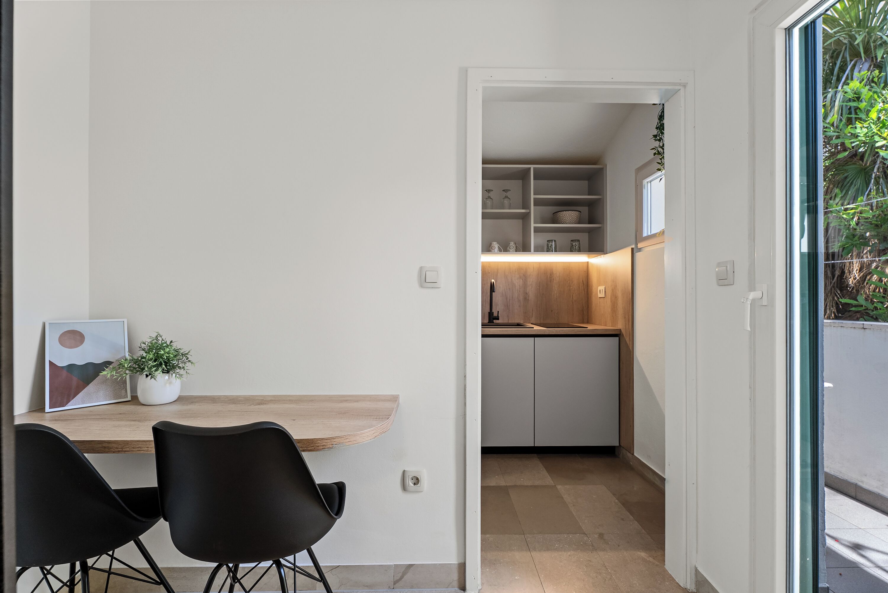 Une cuisine moderne avec des armoires blanches, un plan de travail en bois et une vue sur l’extérieur.