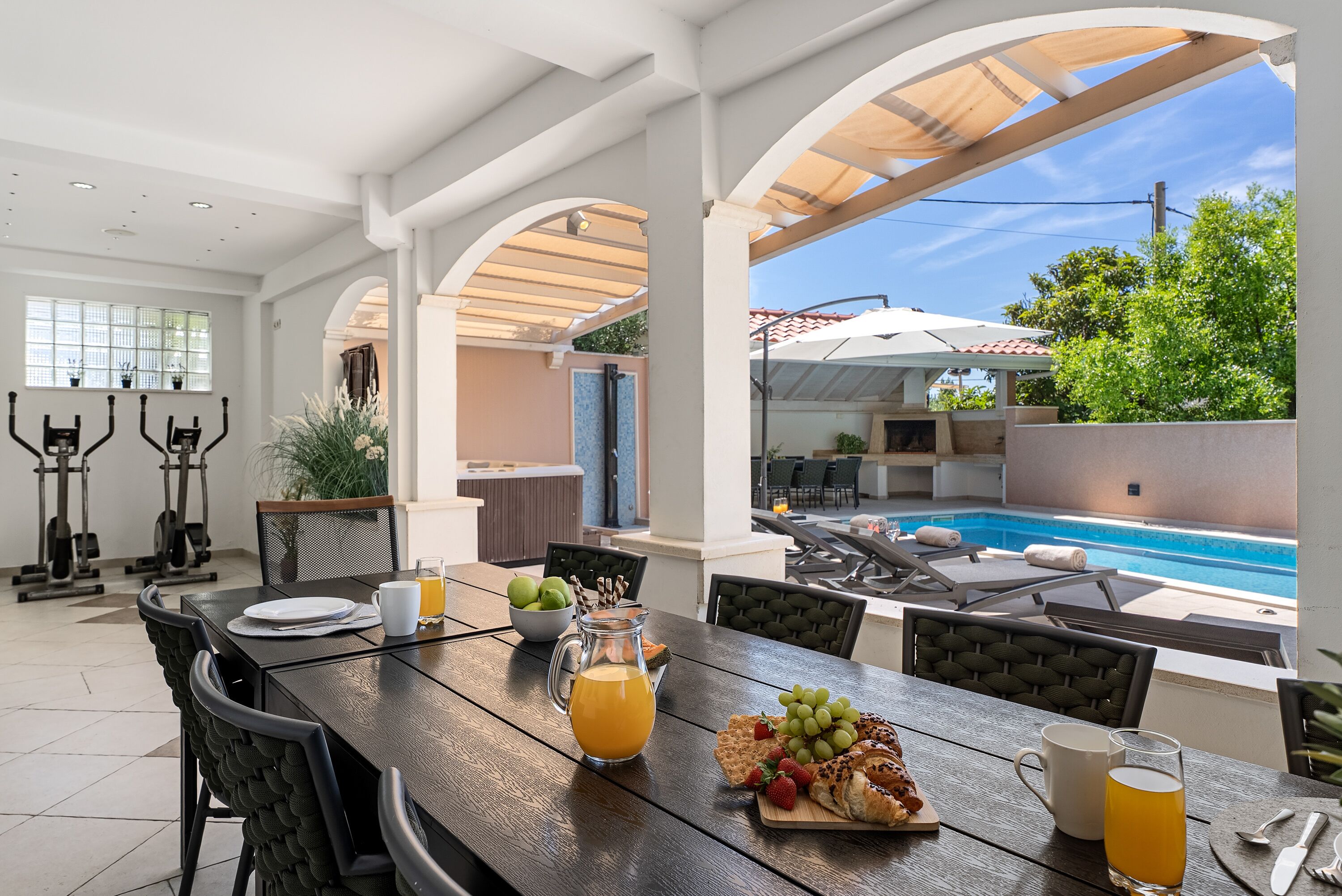 A dining area with a pool view, outdoor seating, and exercise equipment.
