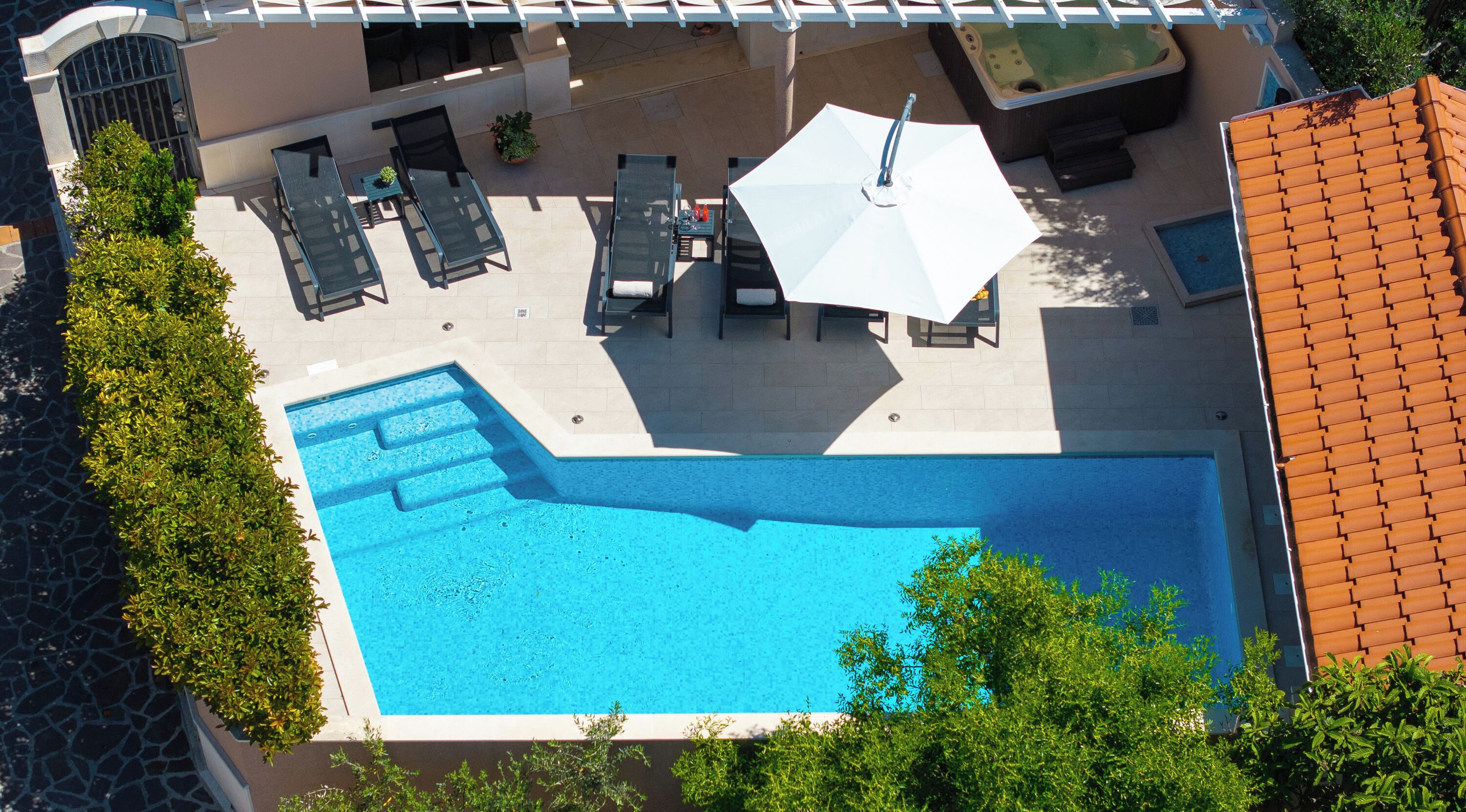An aerial view of a swimming pool with lounge chairs and a hot tub.