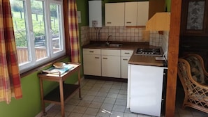 Eine kleine Küche mit Fenster, Tisch und Kühlschrank.