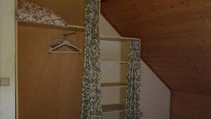 Un dormitorio con cama, techo de madera y un armario con perchero.