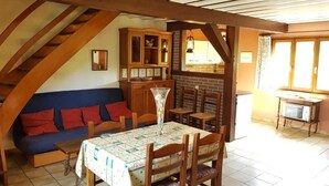Un comedor acogedor con una mesa y sillas de madera, un sofá azul y una pared de ladrillo.