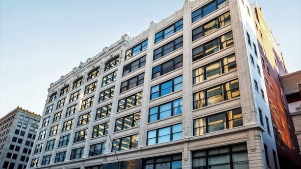 Un edificio de varios pisos con fachada simétrica, ventanas amplias y una entrada en esquina.
