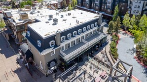 A multi-story building with a flat roof, large windows, and a covered outdoor seating area. - Walk to Skiing, Stunning Top Floor Condo at Park City Base, Professionally Decorated Luxury 3BR (Park City)