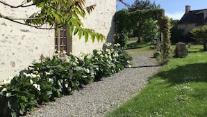 Ein Kiesweg führt zu einem weißen Gebäude mit Fenster und Tür.