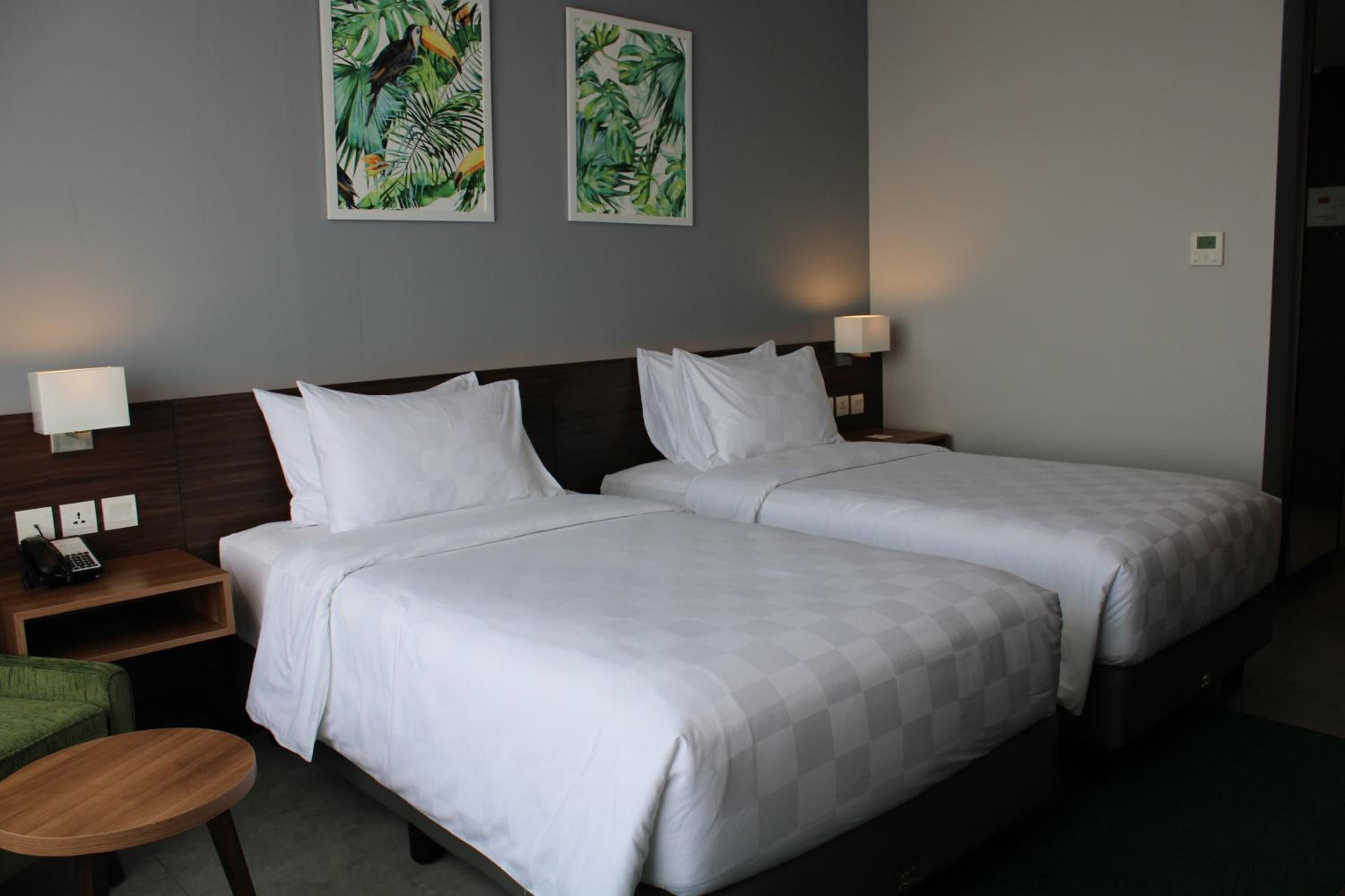 Ein Hotelzimmer mit zwei Betten, einem kleinen Tisch und zwei Wandlampen.
