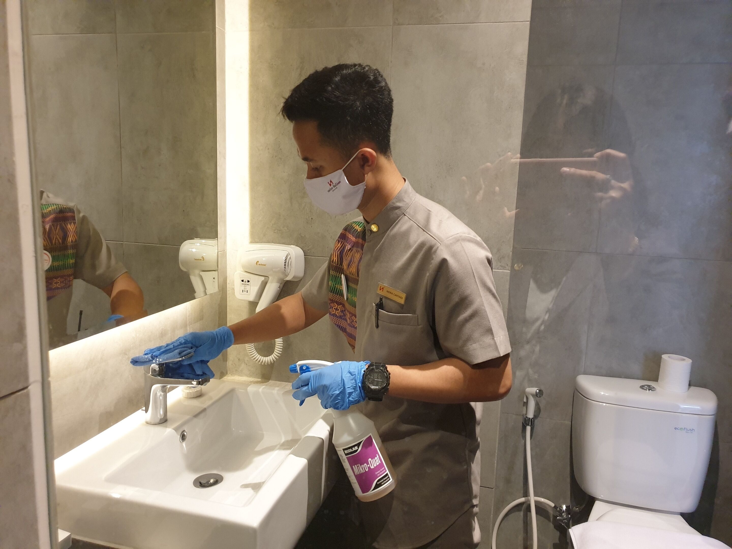 A person cleaning a bathroom sink with a spray bottle.