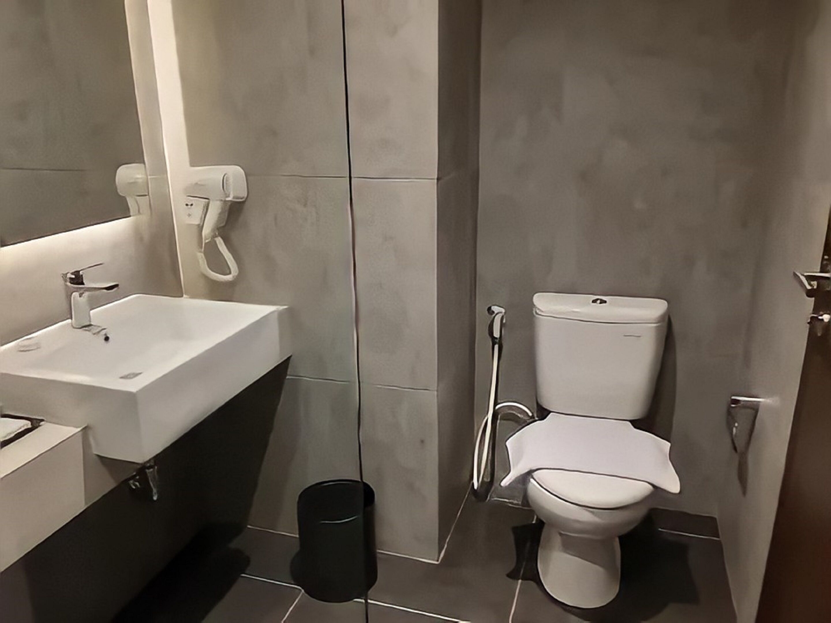 A modern bathroom with a white sink, mirror, and toilet.
