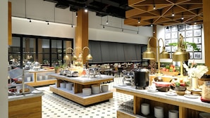 Un restaurante moderno con detalles de madera y suelo de baldosas, que cuenta con varias mesas y una variedad de platos exhibidos.